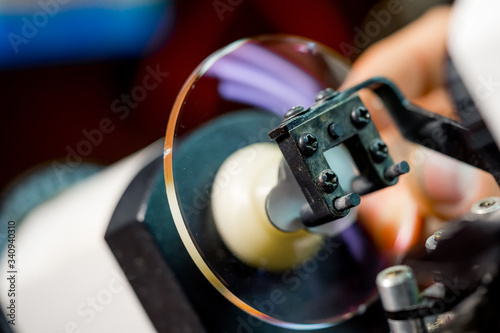 Glasses manufacturing process.Health care. Man polishing glasses in optical shop. Grind the lens into the eyeglass.