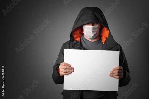 A man in a jacket with a hood and a mask holds a tablet with a swipe for text