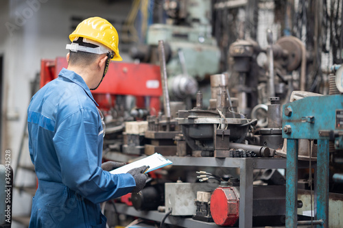 engineer checking metal component at machine receptacle in factory photo
