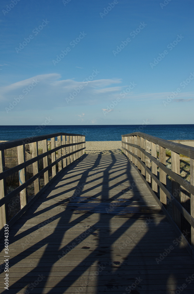 Lights and shadows on a wooden bridge leading to the sea