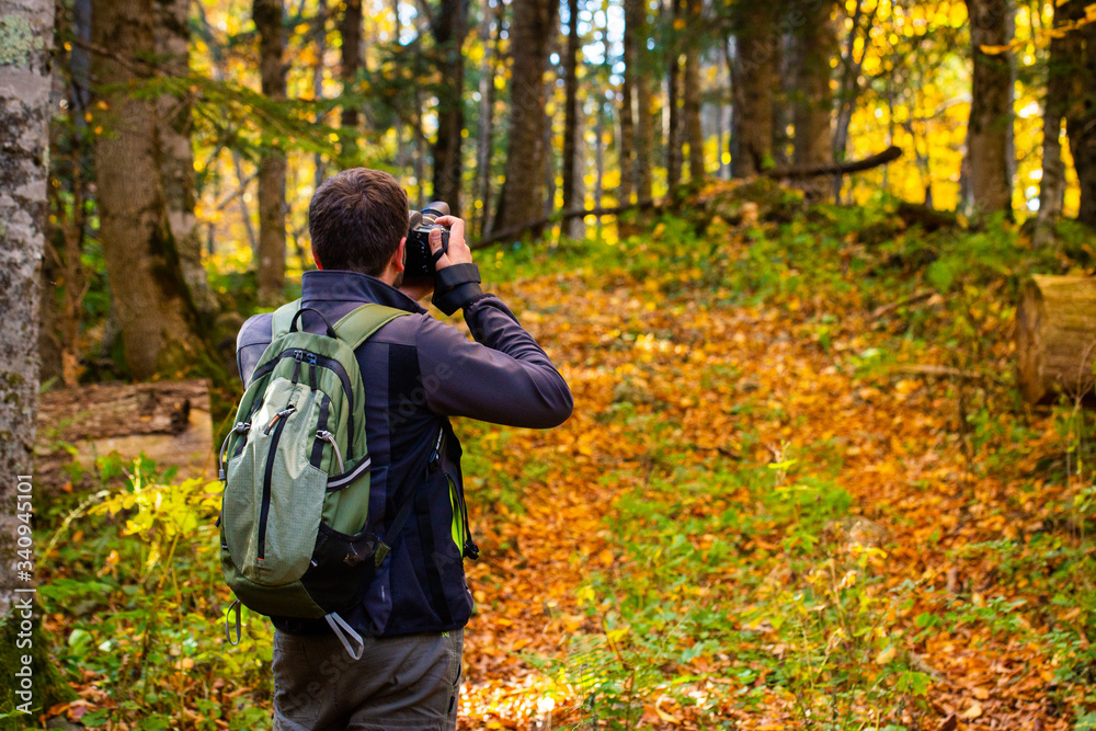 Back view male photographer in bright autumn forest