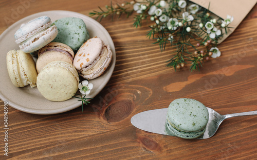 Colorful homemade macarons are lying on theplate on the brown wooden background. Envelope with blossom. photo