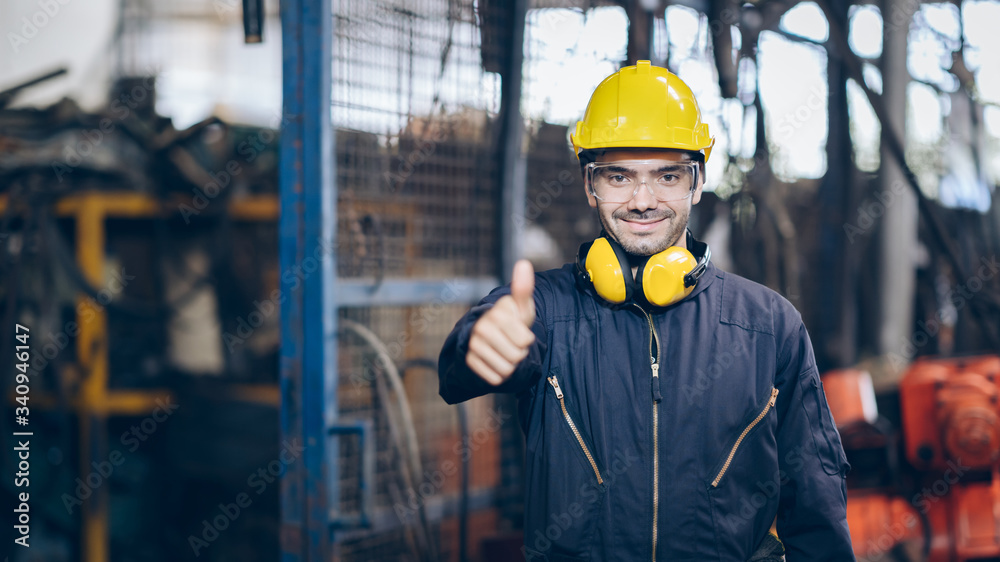 Smile technician Engineer man thump up and hold portable radio in factory Smile technician Engineer man thump up and hold portable radio in factory