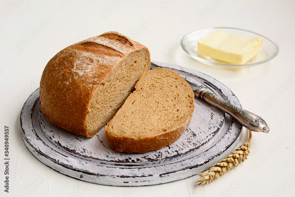 Rye bread, butter and knife on a wooden plate on a white background Rye bread, butter and knife on a wooden plate on a white background