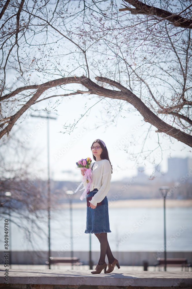 beautiful girl walks with a bouquet of spring flowers along the promenade