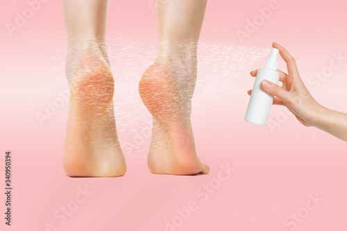 Women's feet standing on tiptoes, and a hand that sprays cosmetics or medicine on the heel. Pink background. The concept of freshness, hydration and protection of the skin of the feet