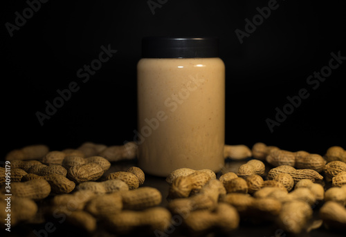 Ripe peanuts in husk and jar with peanutbutter photo