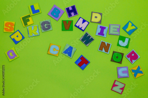 Alphabet. All letters of the alphabet in one place. Multicolored, beautiful letters. ABC. Occupation with children. Learning letters. English. Green background. Female hands hold letters. Words cat