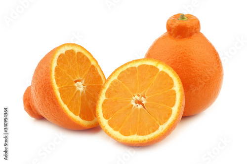 one fresh minneola and a cut one on a white background