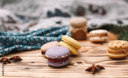 Homemade colorful macaroons are lying on the brown wooden table. Cup of coffee. Anise, honey and colorful tissue.