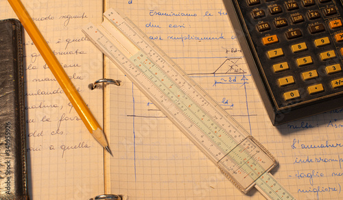 Pencil, old slide rule and scientific electronic calculator page with the calculations in progress