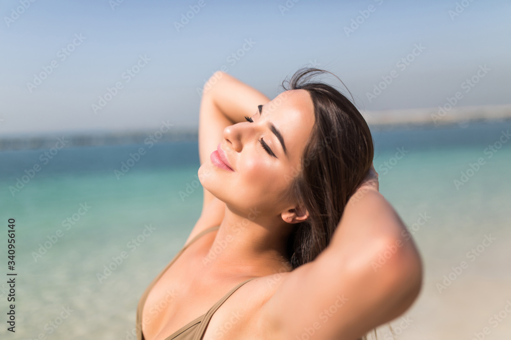 Portrait of a girl relaxing on the beach raised her hands up and closed over her head