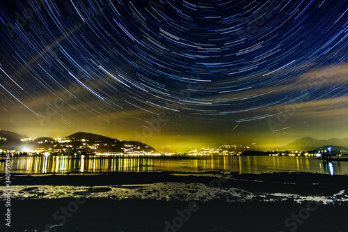 Fotografi lake maggiore in italy at night with star trails around