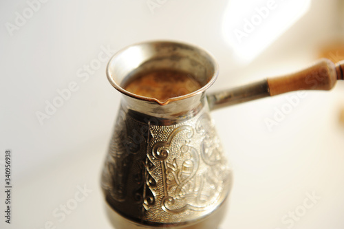 Cooper cezve coffee brewing on white background close up