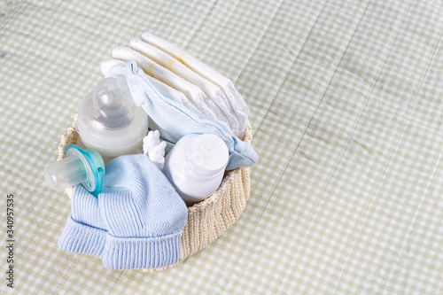 Newborn baby care products. Lotion, powder and diapers on changing table in nursery. Baby's nipple, bottle and socks in knitted basket. Baby cosmetics and hygiene concept. Top view. photo