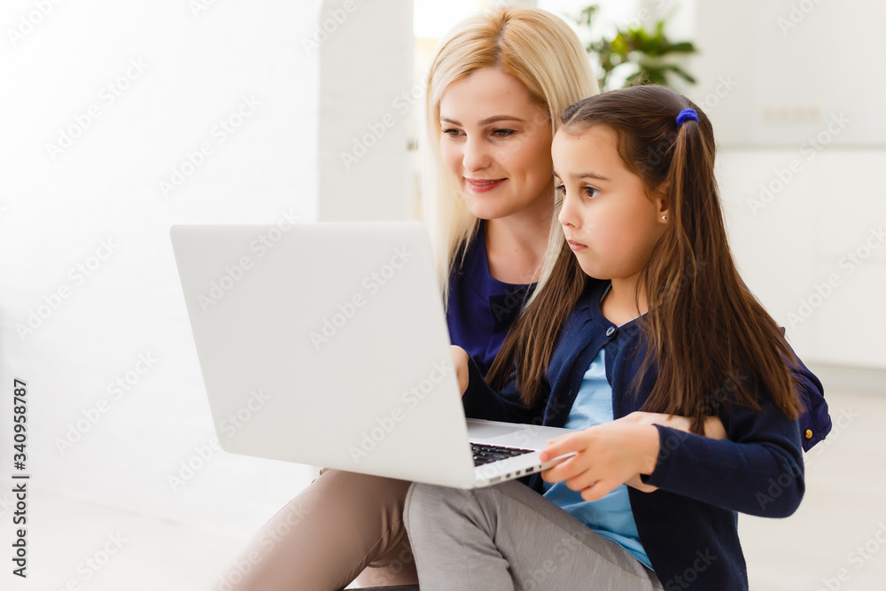 Beautiful woman helping her daughter doing her homework in a kitchen Beautiful woman helping her daughter doing her homework in a kitchen