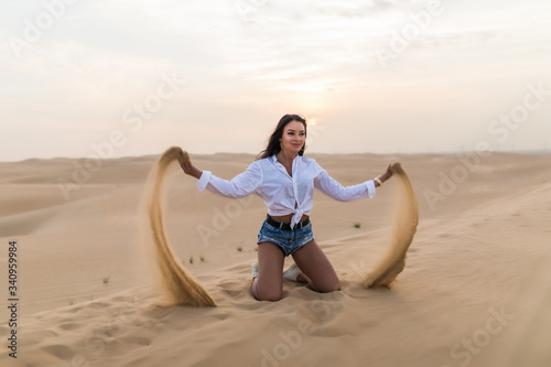 Young sexy woman playing with sand in the dunes desert.