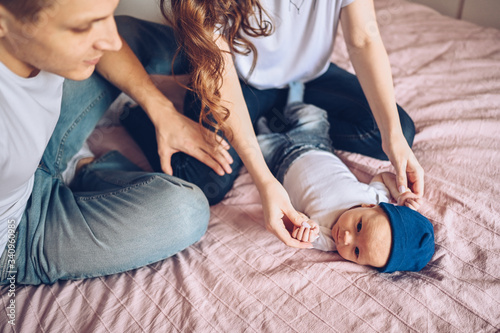 Close up portrait of a happy parents holding their baby. Young happy family, mom and dad playing with cute emotional little newborn child son in the bedroom