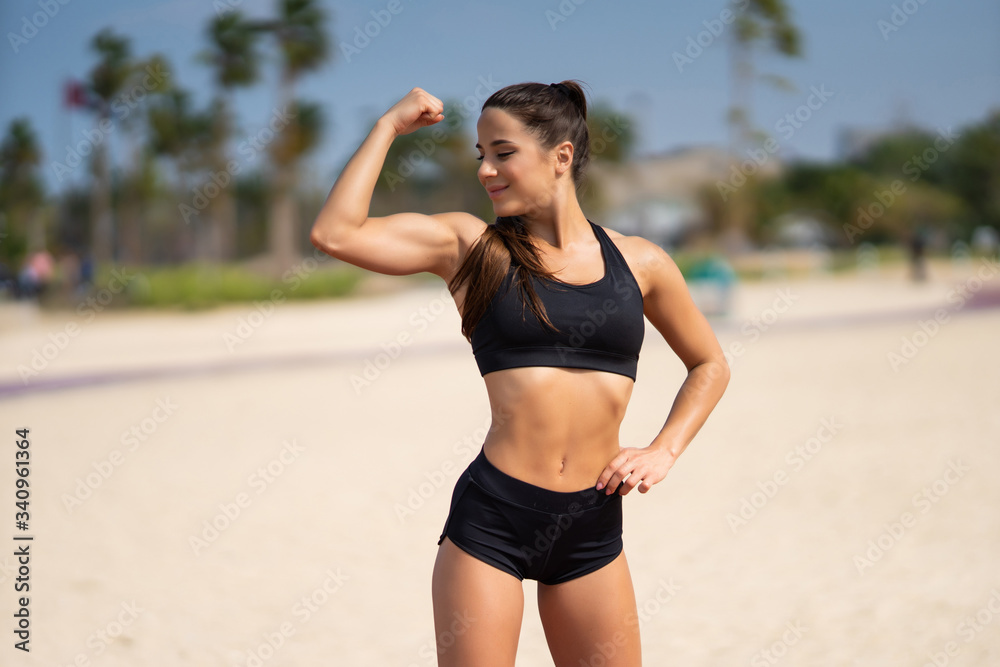 Strong fitness woman showing arms biceps towards the sea. Healthy lifestyle motivation and success. Strong fitness woman showing arms biceps towards the sea. Healthy lifestyle motivation and success.