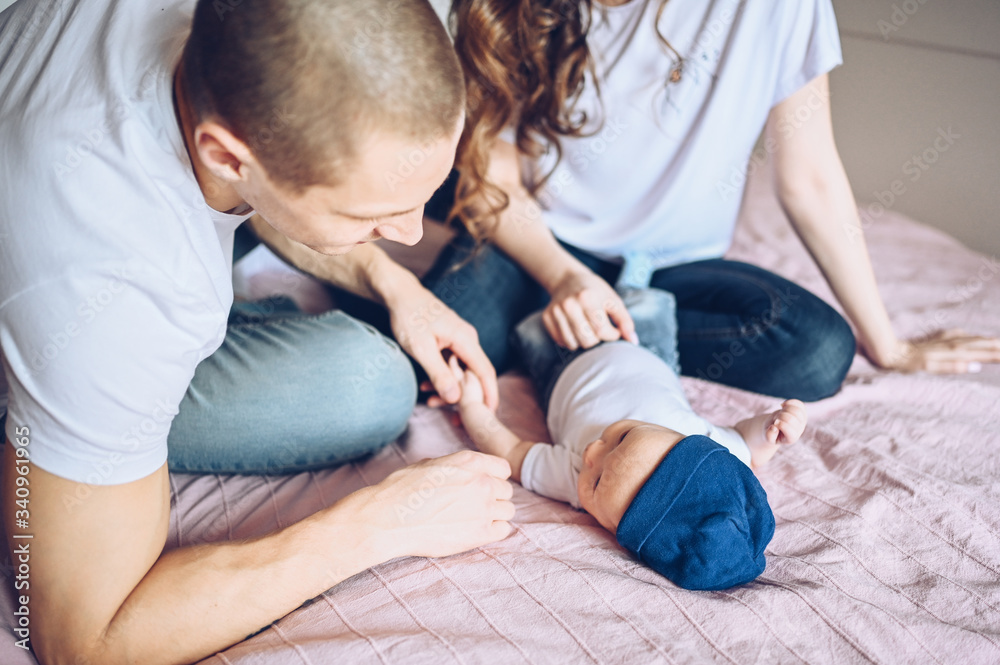 Close up portrait of a happy parents holding their baby. Young happy family, mom and dad playing with cute emotional little newborn child son in the bedroom Close up portrait of a happy parents holding their baby. Young happy family, mom and dad playing with cute emotional little newborn child son in the bedroom