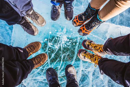 Traveller people foot standing on cracks surface of the natural ice in frozen water at Olkhon Island, Baikal lake, Russia photo