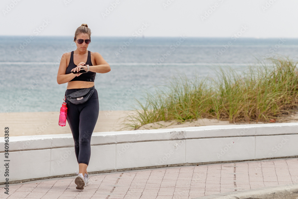 young woman walking and jogging on the beach wearing yoga pants