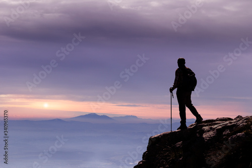 hiker on mountain peak at sunset