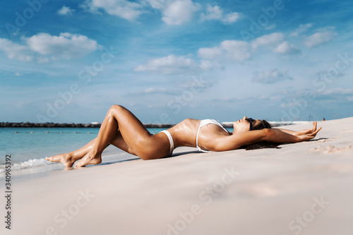 Young attractive girl in white swimsuit lying on the beach