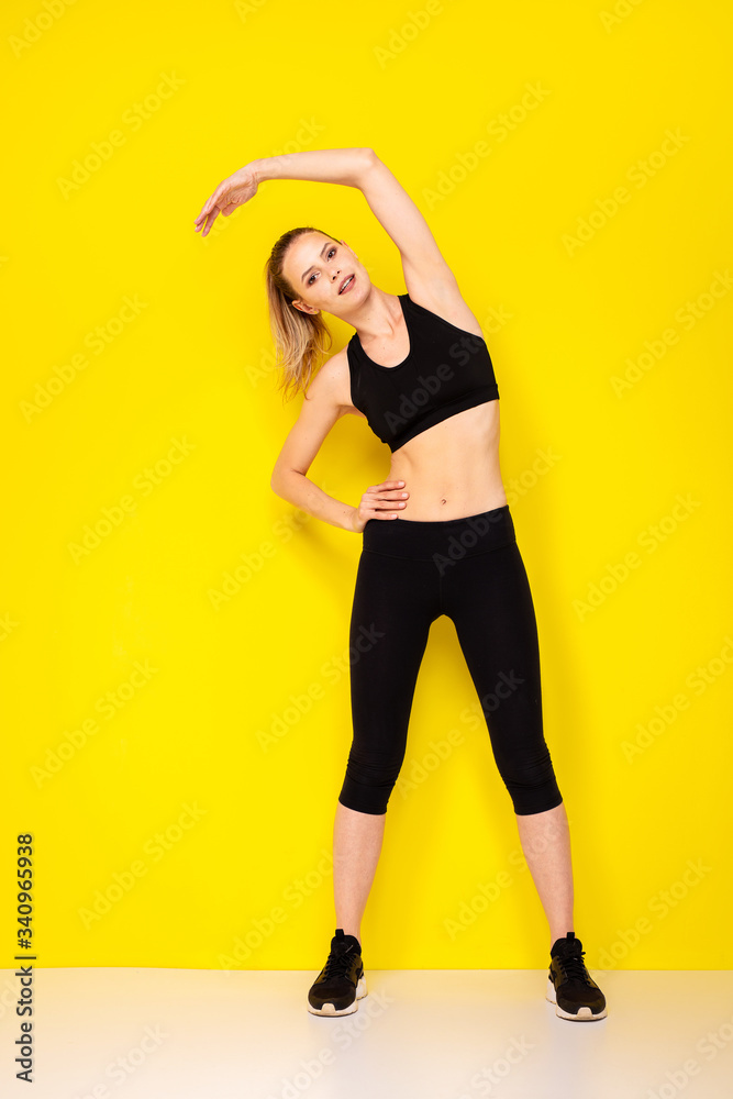 young woman doing exercise on yellow background young woman doing exercise on yellow background
