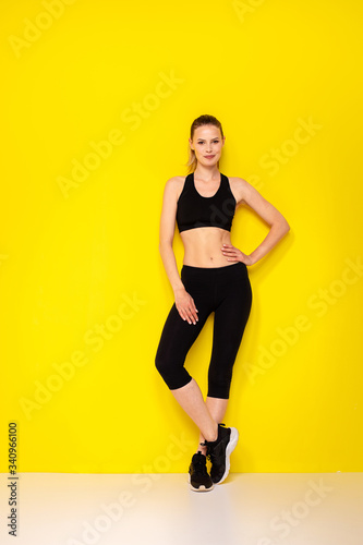 young woman doing exercise on yellow background