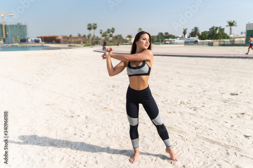 Young beautiful woman making stretching exercises in the beach