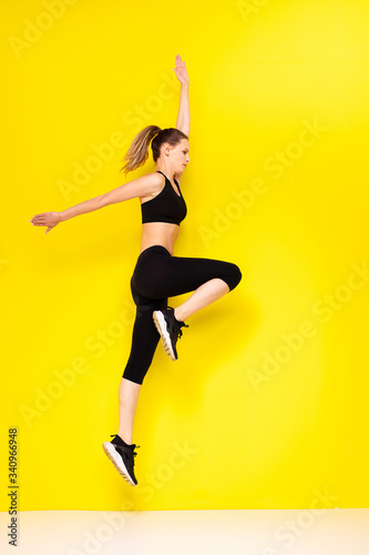 young woman doing exercise on yellow background