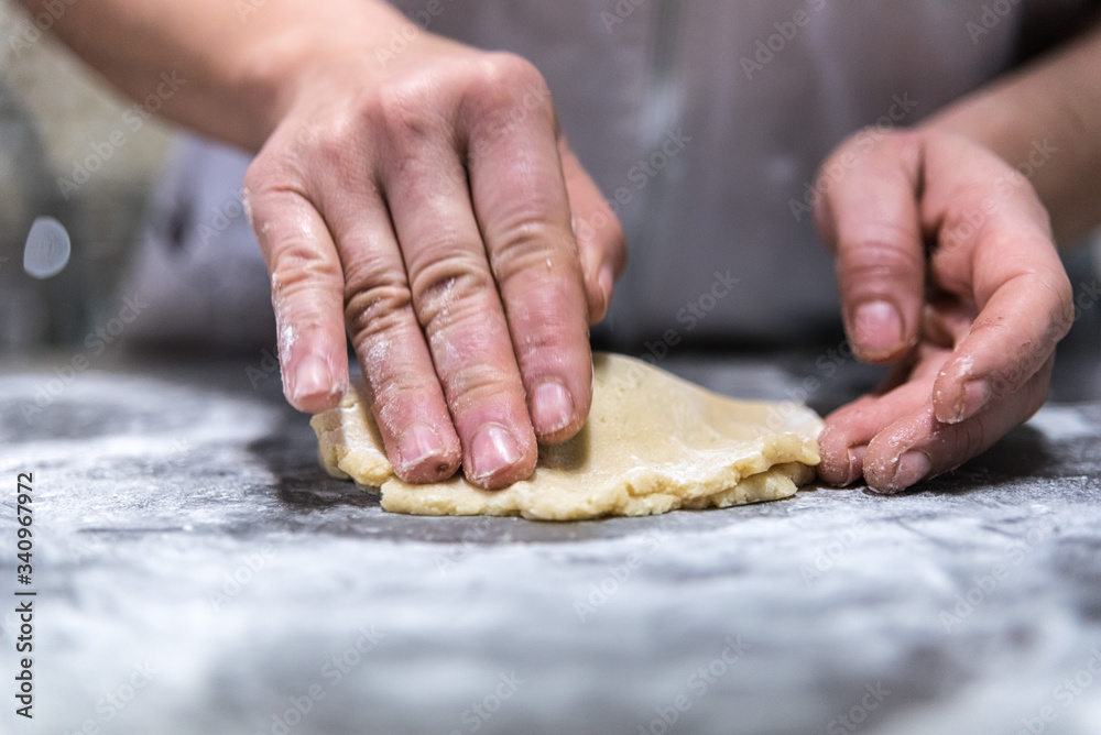 Unrecognizable chef rolling sweet jam into raw dough while cooking pastry on table in bakery Unrecognizable chef rolling sweet jam into raw dough while cooking pastry on table in bakery