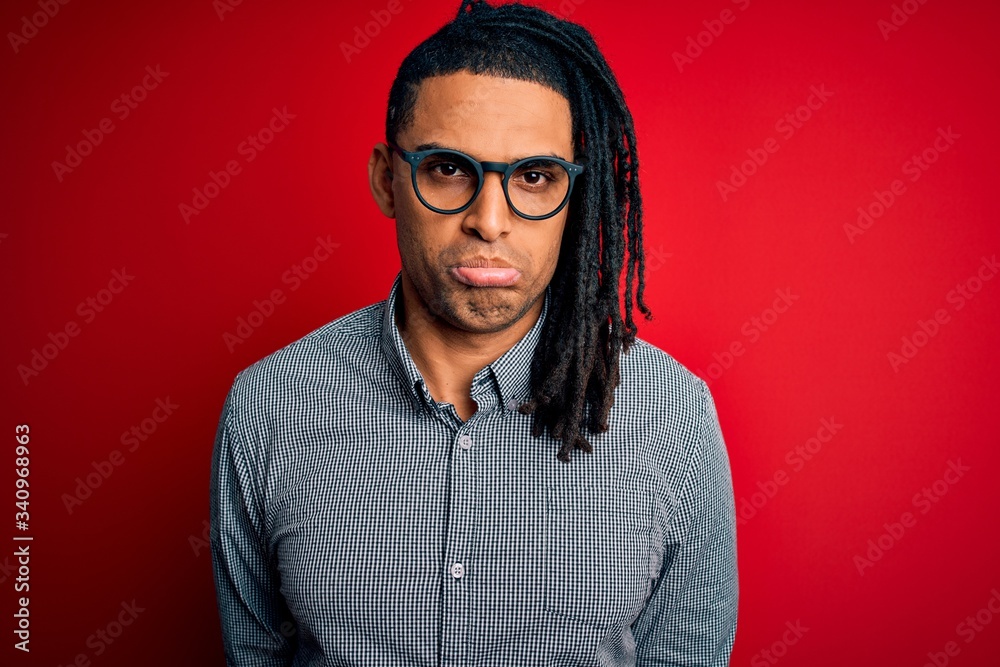 Obraz premium Young handsome african american man with dreadlocks wearing casual shirt and glasses depressed and worry for distress, crying angry and afraid. Sad expression.