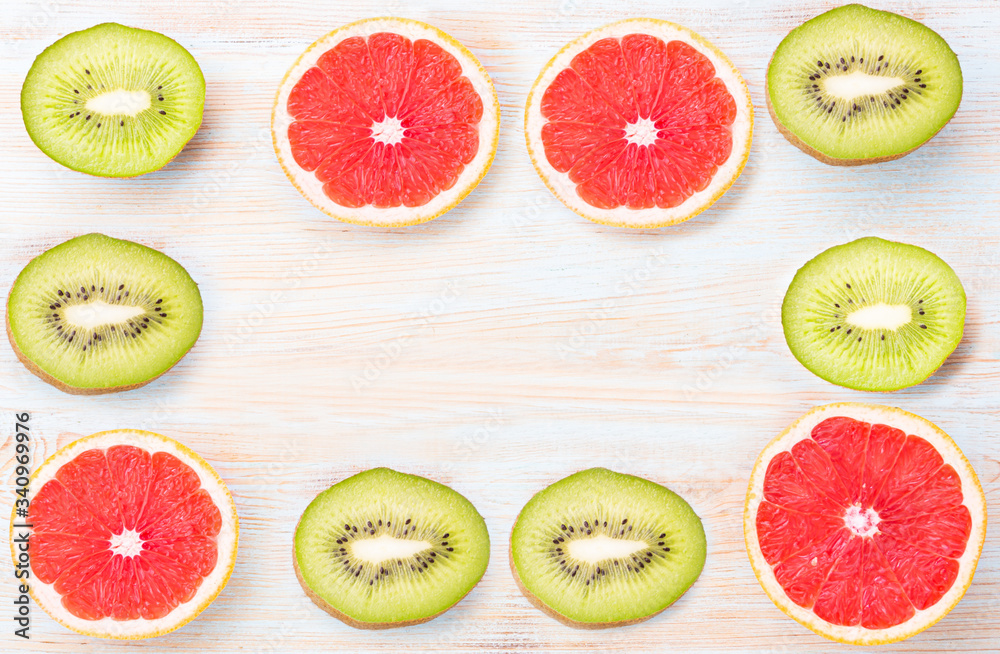 Fototapeta premium Top view of sliced citrus fruits grapefruit and kiwi on blue table.