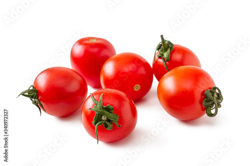 Small, red cherry tomatoes with green cuttings, on a white background