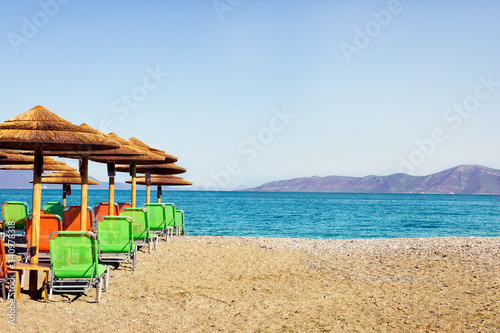 Fototapeta Naklejka Na Ścianę i Meble -  Palm parasols with empty chairs, beautiful beach
