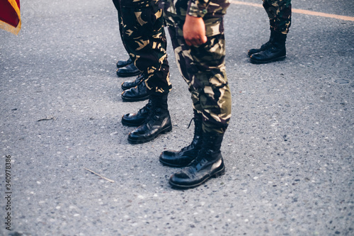 Obraz na plátně Low section shot of military in camouflage pants and black boots standing on concrete ground