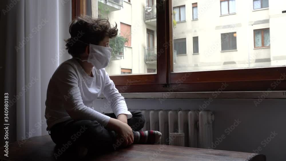 Europe, Italy , Milan - children boy five years with mask at home during quarantine at home due n-cov19 Coronavirus outbreak - life style in apartment - look and say hello from the window rainy day Europe, Italy , Milan - children boy five years with mask at home during quarantine at home due n-cov19 Coronavirus outbreak - life style in apartment - look and say hello from the window rainy day
