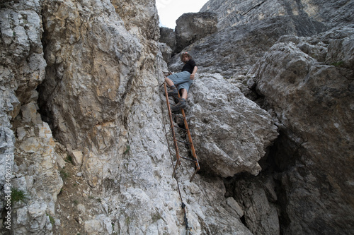 Tourist standing on a ladder on the via ferrata trail in the Dolomites