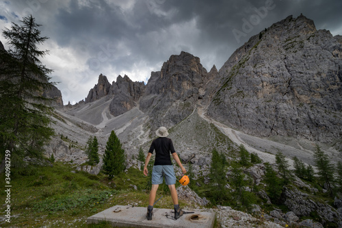 A man standing with a helmet in his hand and admiring the peaks of the Dolomites