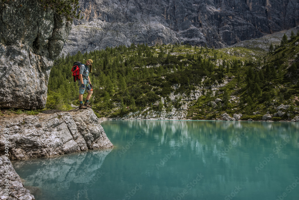 Tourist posing for a photo against the background of the beautiful Lago di Sorapis lake in the Italian Dolomites