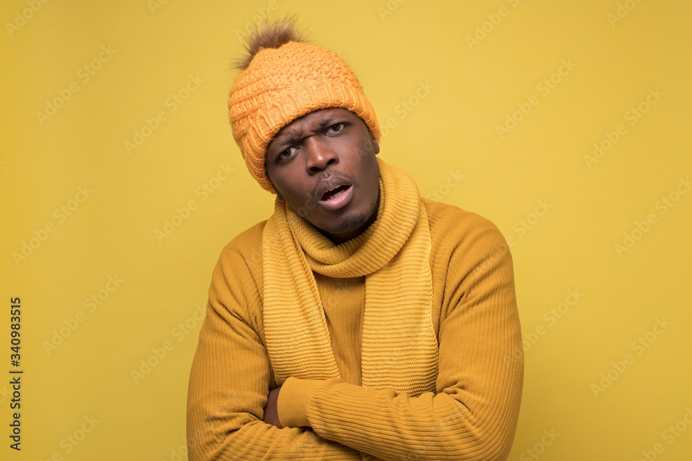 African man in warm hat and scarf looking at camera with confused expression African man in warm hat and scarf looking at camera with confused expression
