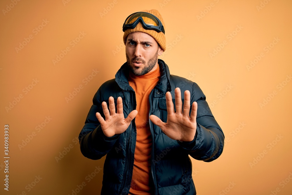 Young handsome skier man with beard wearing snow sportswear and ski goggles  Moving away hands palms showing refusal and denial with afraid and  disgusting expression. Stop and forbidden. Stock Photo | Adobe