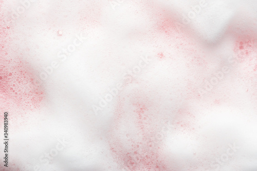 White cosmetics foam texture on pink backdrop. Cleanser, soap, shampoo bubbles. Foamy skin care product sample. Skincare, cosmetology and beauty concept