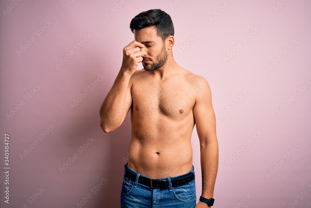 Young handsome strong man with beard shirtless standing over isolated pink background tired rubbing nose and eyes feeling fatigue and headache. Stress and frustration concept. Young handsome strong man with beard shirtless standing over isolated pink background tired rubbing nose and eyes feeling fatigue and headache. Stress and frustration concept.