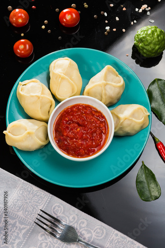 Cooked dumplings mantas on a green plate on black background