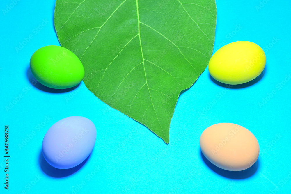 Beautiful easter eggs and green leaves on a blue background Beautiful easter eggs and green leaves on a blue background