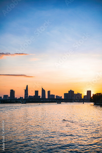 River city view landscape at twilight sunset. Boat on river with tranquil water. Hochiminh city Saigon vietnam cityscape building with Bitexco tower © CravenA