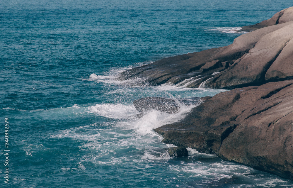 Ocean waves crash against stone shores